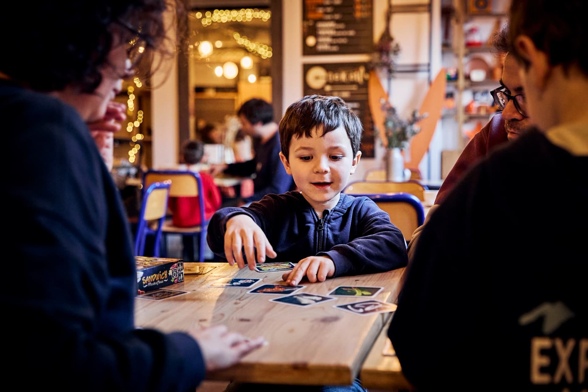 Jeune enfant jouant aux cartes avec des adultes